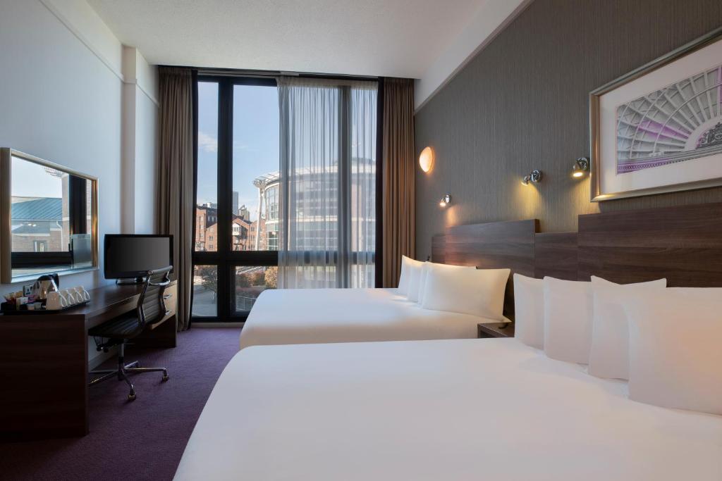 a hotel room with two beds and a large window at Leonardo Hotel Leeds in Leeds