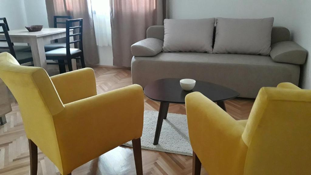 uma sala de estar com cadeiras amarelas e um sofá em Apartman river side em Sokobanja