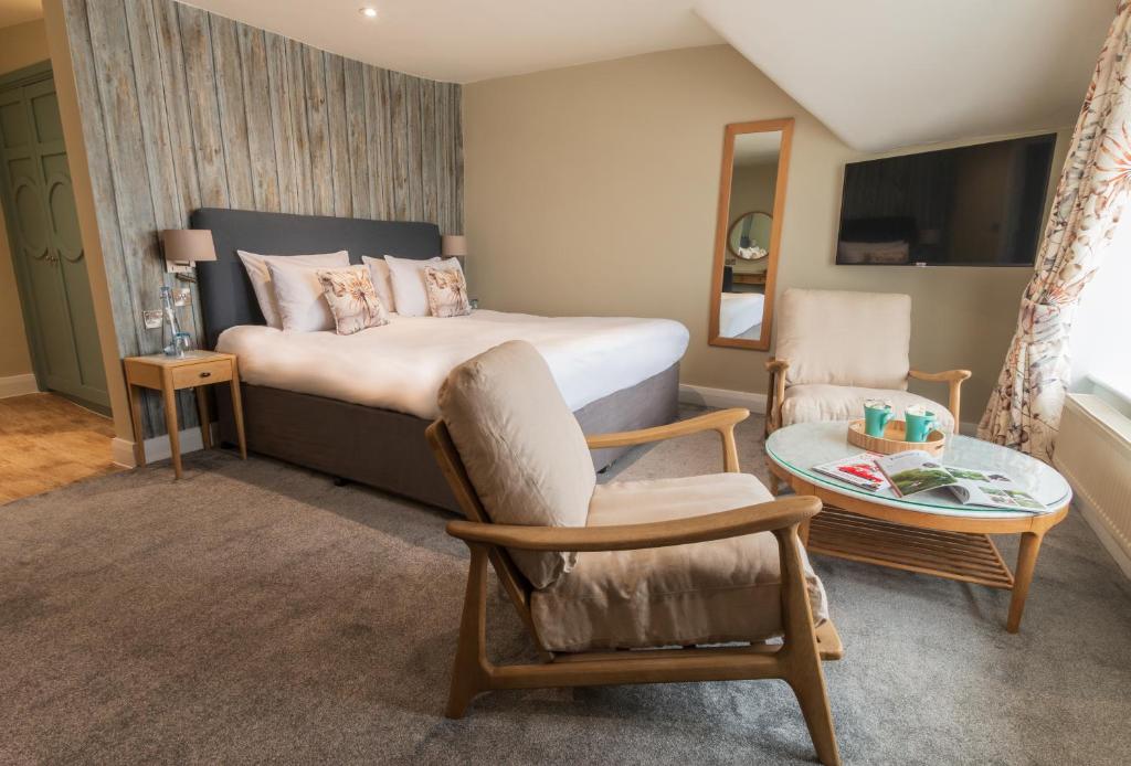 a bedroom with a bed and a chair and a table at The Brudenell in Aldeburgh