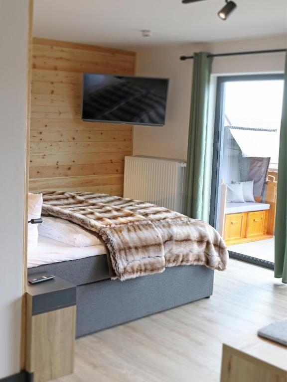 a bedroom with a bed and a tv on a wall at BergButzen mit Balkon in Braunlage