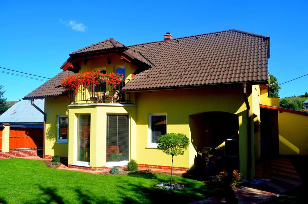 una casa amarilla con un balcón con flores. en Vila Deluxe - Liptov, Bešeňová, en Bešeňová