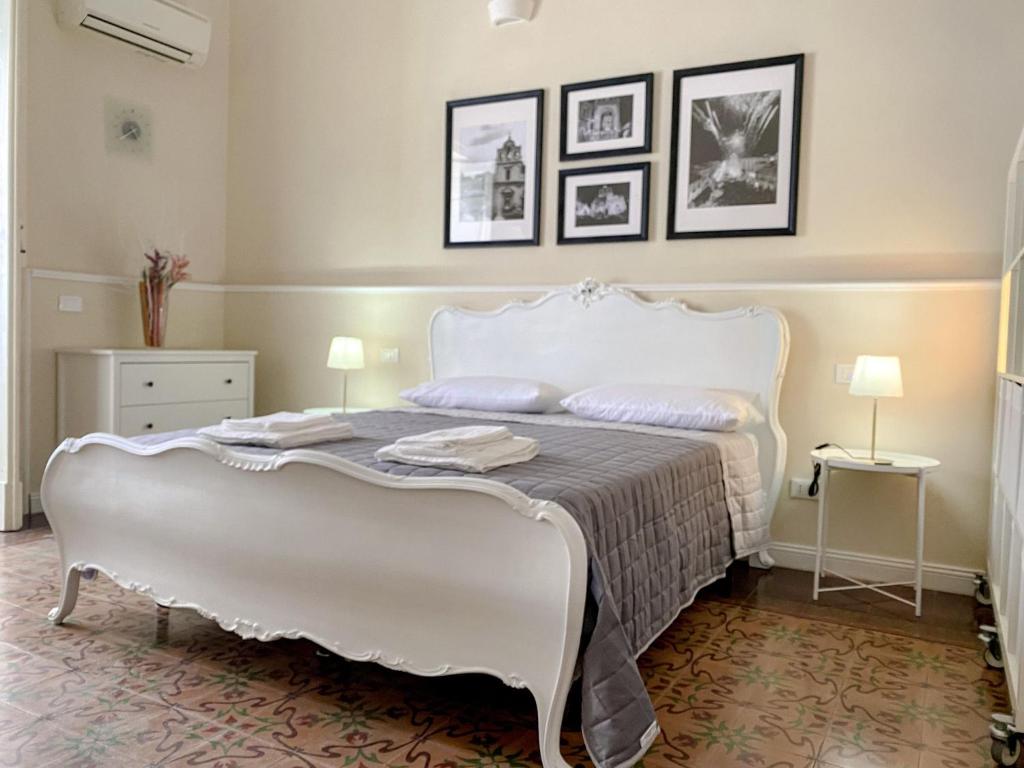 a white bed in a room with pictures on the wall at Duomo Rooms b&b in Lentini