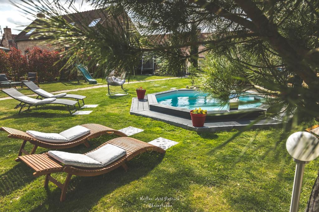 een tuin met stoelen en een zwembad bij Au Domaine Fresnois in Fresnes-lès-Montauban