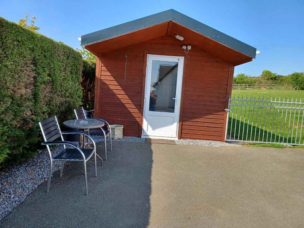 un pequeño cobertizo con sillas y una mesa delante de él en Dunroaming Cabin, en Pendine