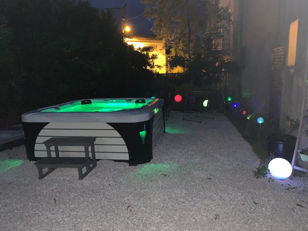 a pool table in a backyard at night at Les dahlias appartement 4 personnes Jacuzzi Barbecue Jardin arboré Climatisé in Agde