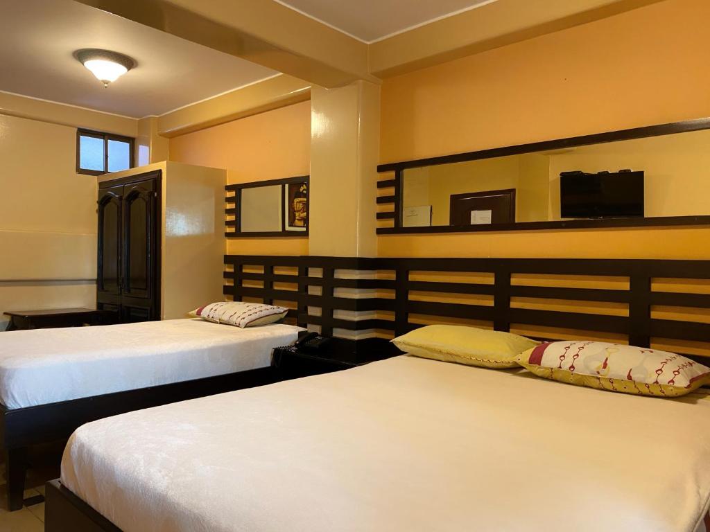 a bedroom with two beds and a mirror at Hostal Montesa in Guayaquil
