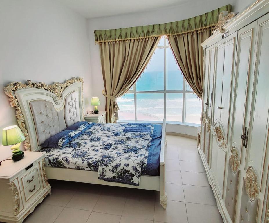 a bedroom with a bed and a large window at Beachfront Holiday Homes in Ajman 