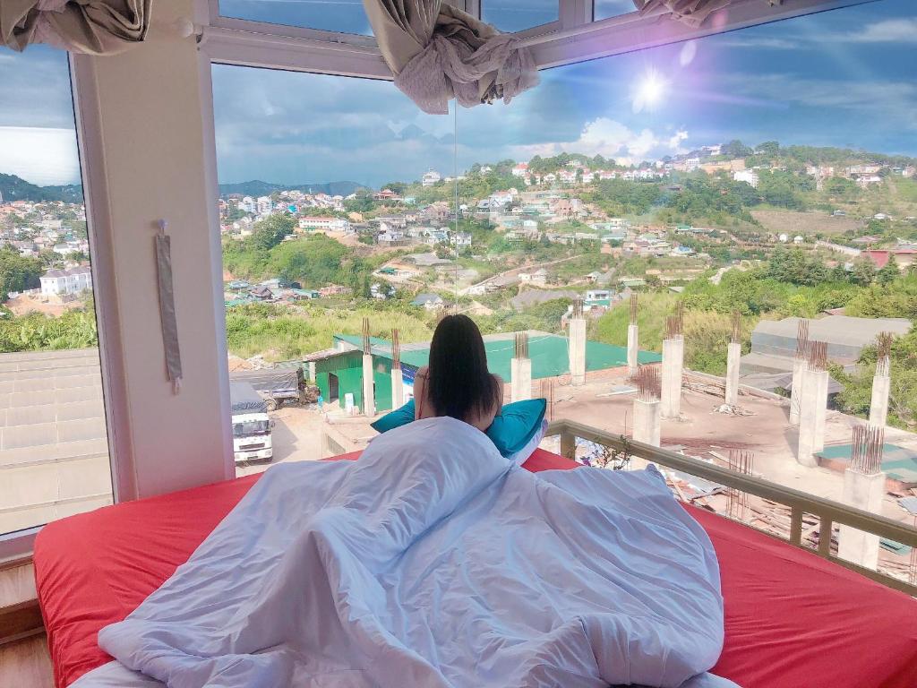 Eine Frau, die auf einem Bett liegt und aus einem Fenster schaut. in der Unterkunft Eco Home Da Lat in Da Lat