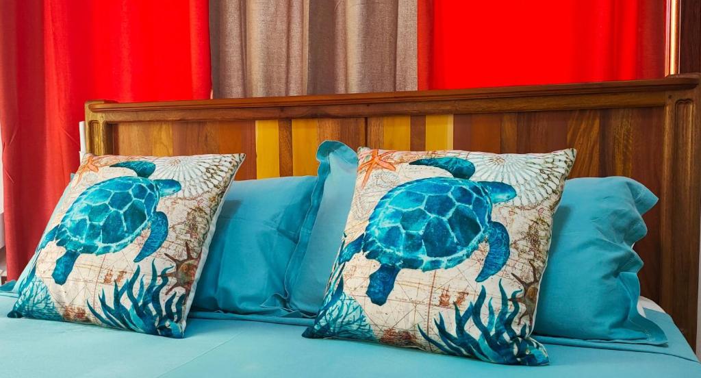 a bed with two pillows with a turtle on it at MT Seaside Apartment in La Digue