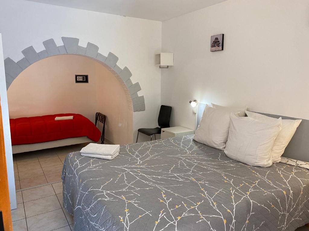 una camera con un grande letto e un divano rosso di LOGIS Hôtel La Chaumière a Marseillan