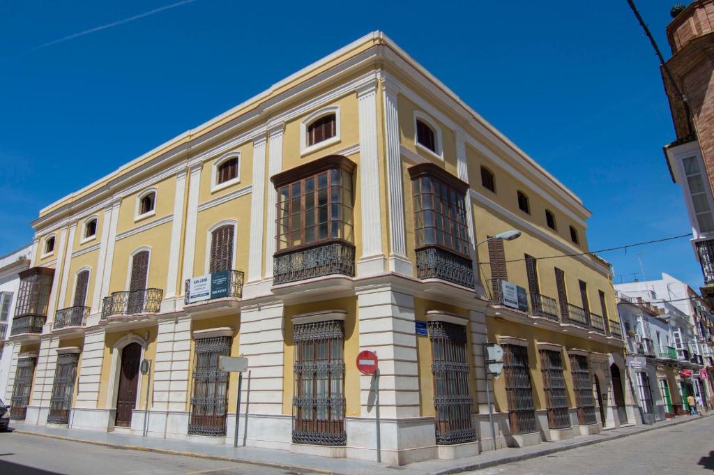 żółty budynek na poboczu ulicy w obiekcie Ático San Juan, Apartamentos Living Sur w mieście Sanlúcar de Barrameda