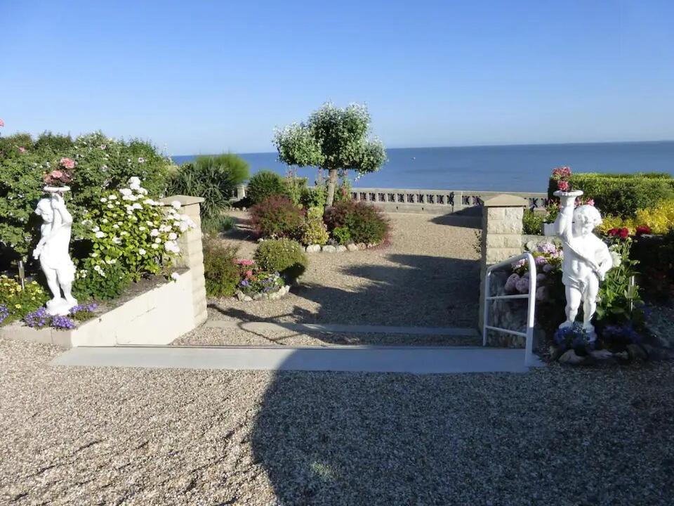 un jardin avec deux statues blanches sur un mur dans l'établissement EXCEPTIONNEL 3PIÈCES, BALCON, TERRASSE FACE MER, à Villerville