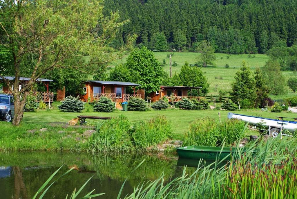 un camarote junto a un lago con un barco en el agua en Stanica pod Zadzierną Kemping Domki letniskowe, en Lubawka