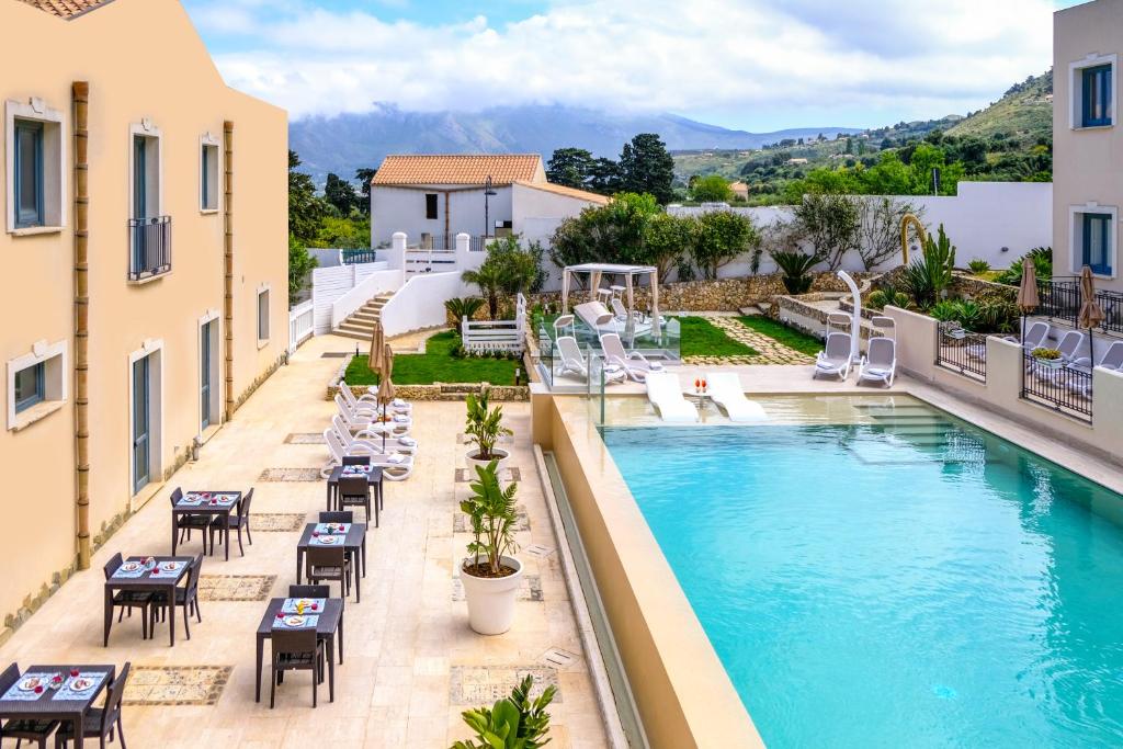 a pool with tables and chairs next to a building at Hotel Baglio Di Scopello in Scopello
