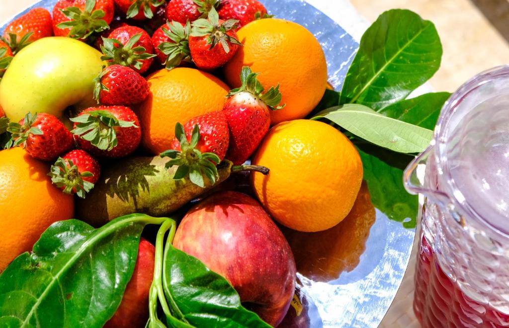 a bowl of fruit with apples oranges and strawberries at Hotel Baglio Di Scopello in Scopello