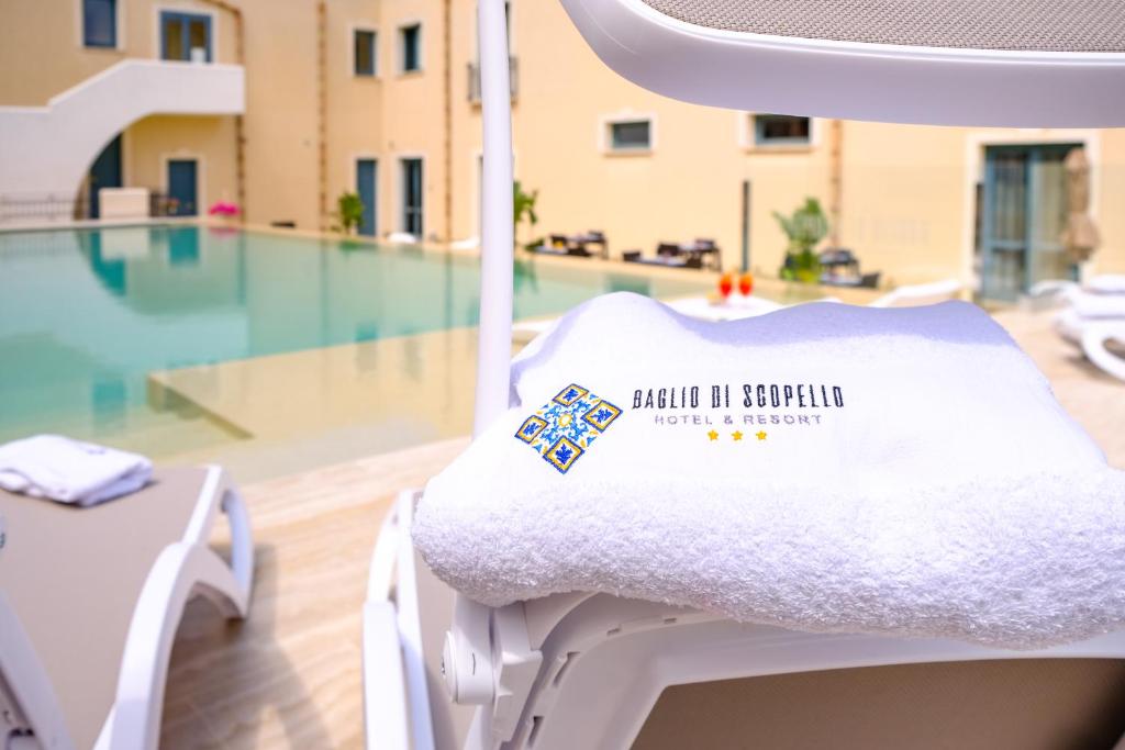a white chair with a sign on it next to a pool at Hotel Baglio Di Scopello in Scopello
