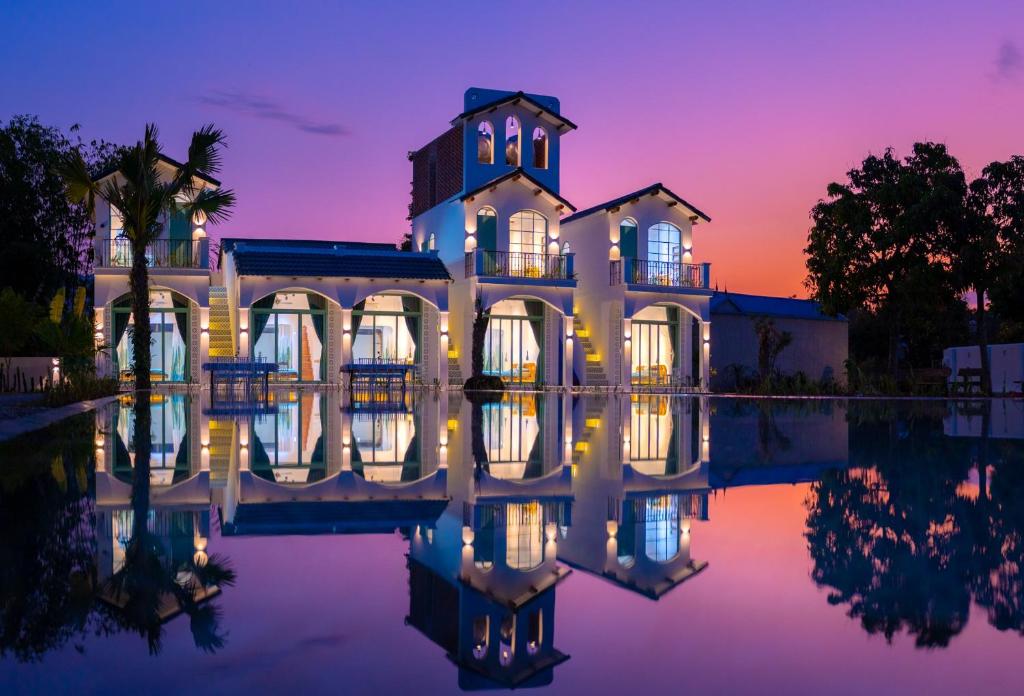 a house with a reflection in the water at sunset at Green Town Mộc Châu in Mộc Châu