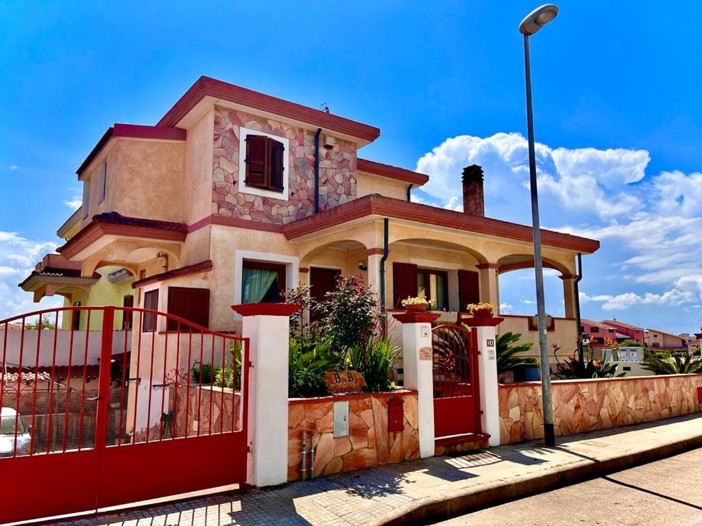 ein Haus mit einem roten Zaun davor in der Unterkunft Il Corallo in Porto Torres