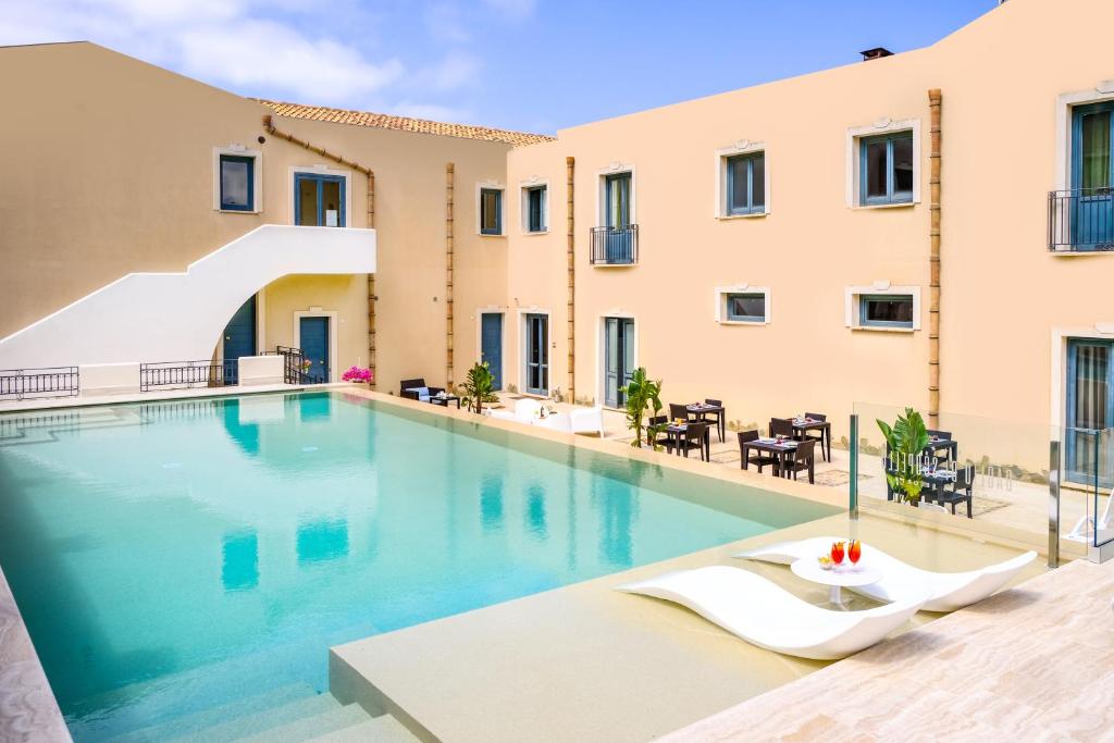 a swimming pool in a hotel with chairs and tables at Hotel Baglio Di Scopello in Scopello