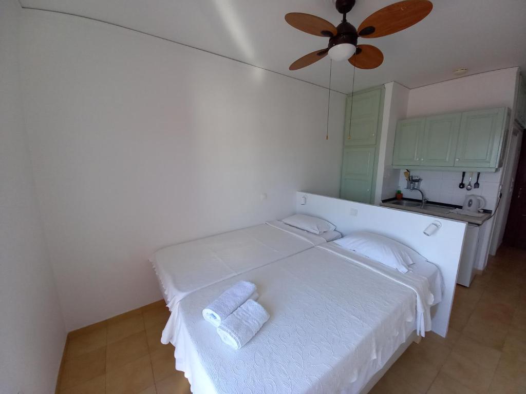 a white bed in a room with a ceiling fan at Evangelia Studios in Sígrion