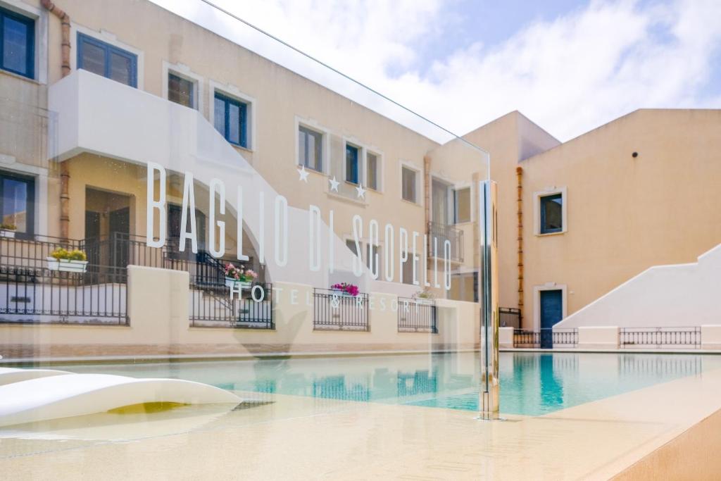 a swimming pool in front of a building at Hotel Baglio Di Scopello in Scopello