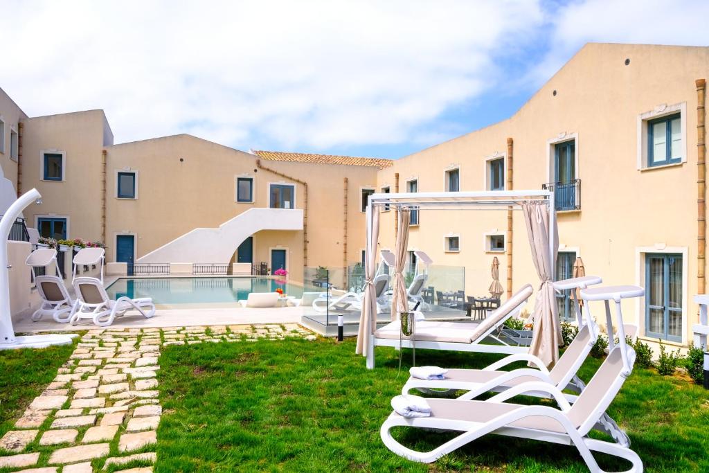 a yard with chairs and a swimming pool at Hotel Baglio Di Scopello in Scopello