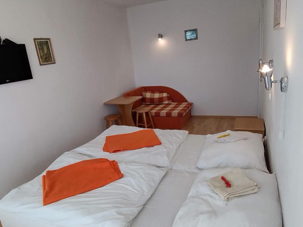 um quarto com duas camas com toalhas cor de laranja em HannaH - Relax dom pod orechom - 2i rodinné štúdio so zdieľanou kuchyňou em Trávnica