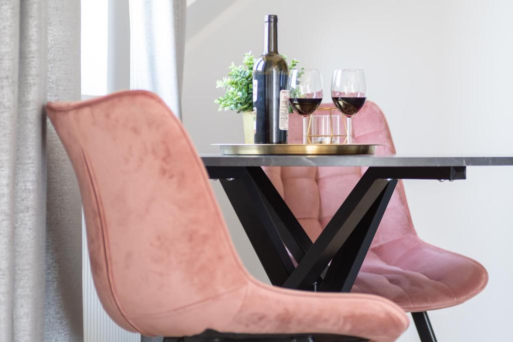 a table with a pink chair and two glasses of wine at PORT 77 in Krynica Morska