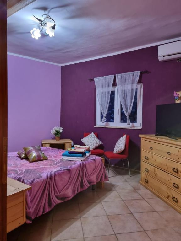 Dormitorio púrpura con cama y TV en Casetta Matilda, en Ardea