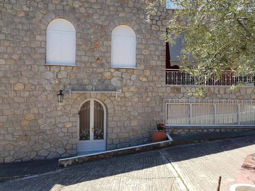 un edificio de piedra con una puerta y tres ventanas en Villa Elea, en Tolo