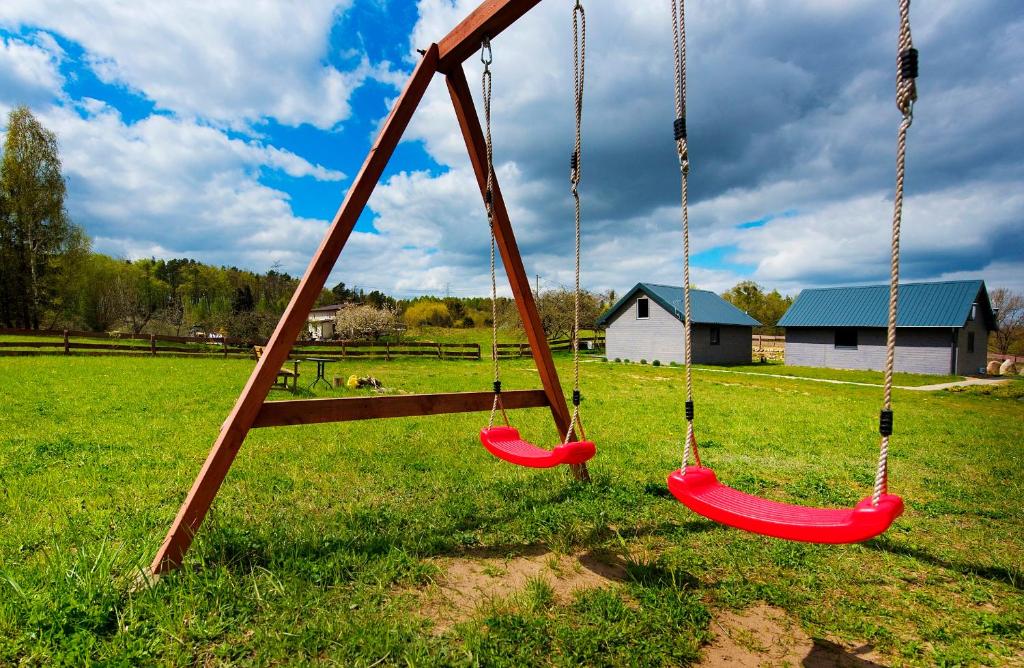 two swings in a field with a house in the background at Domki pod jabłonką in Elganowo