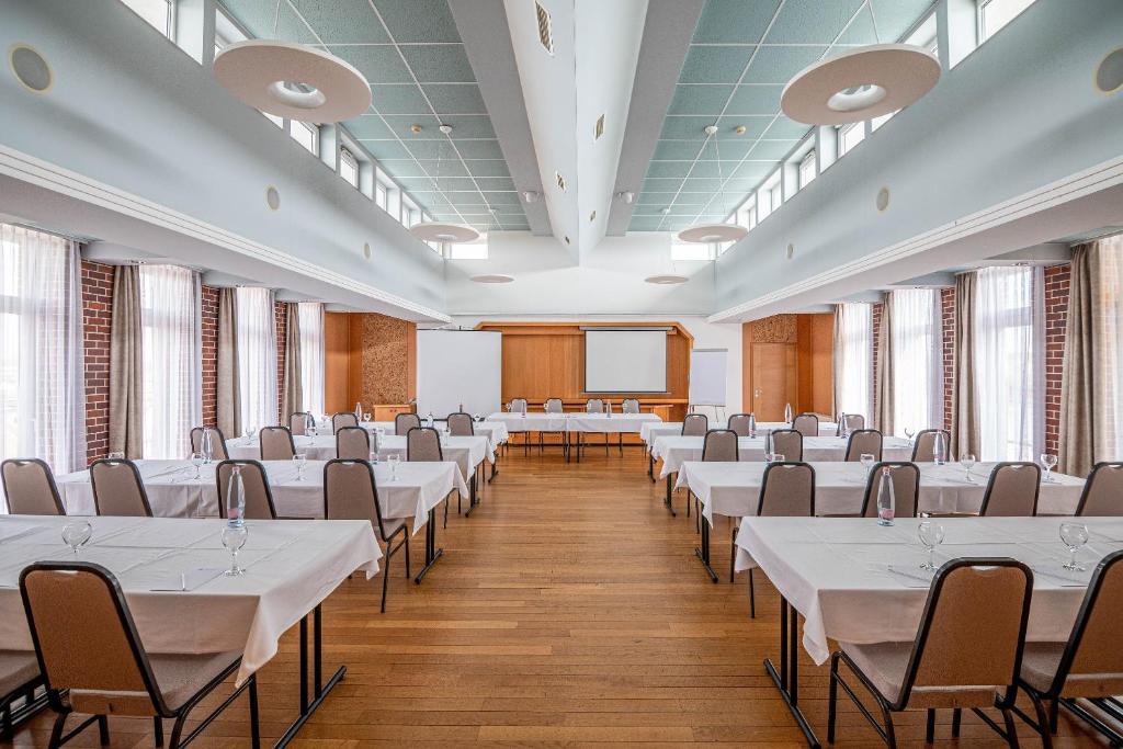 duży pokój ze stołami i krzesłami w obiekcie Szent János Hotel w mieście Mohacz