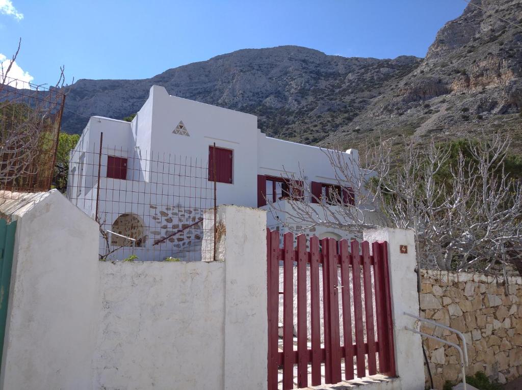 a white house with a fence in front of a mountain at TINA'S HOUSE OUTSTANDING SEASIDE HOUSE Kamares Sifnos in Kamares