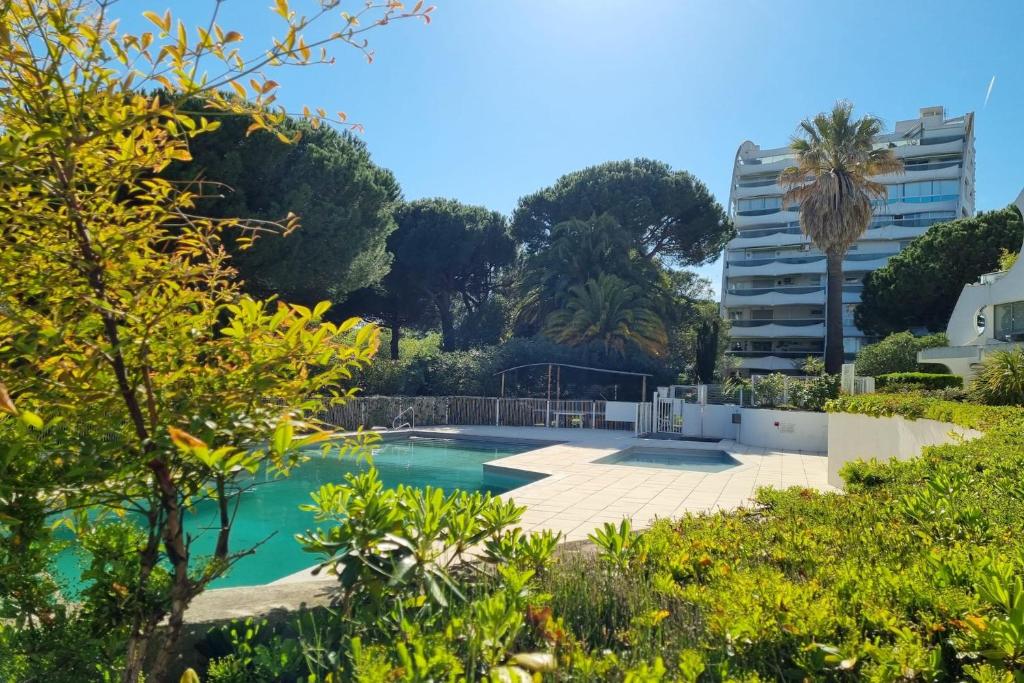 uma piscina num jardim com árvores e um edifício em 39m For 4 Residence With Pool Near Beach em La Grande-Motte