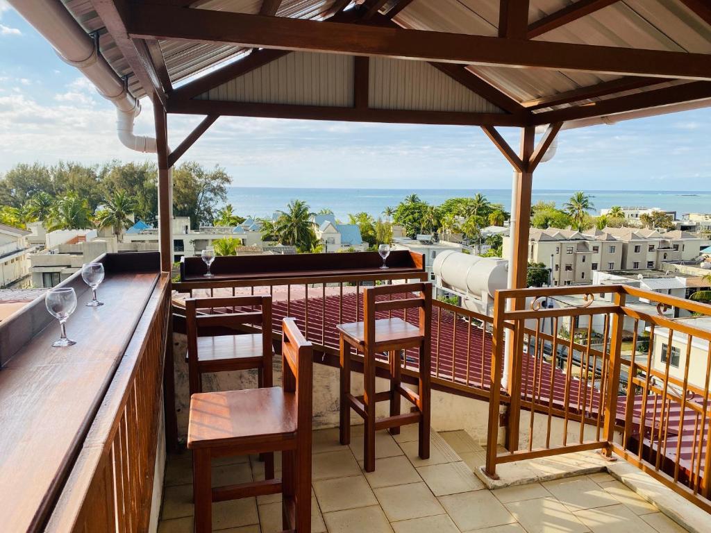 a balcony with tables and chairs and a view of the ocean at Aadi Villa in Mont Choisy