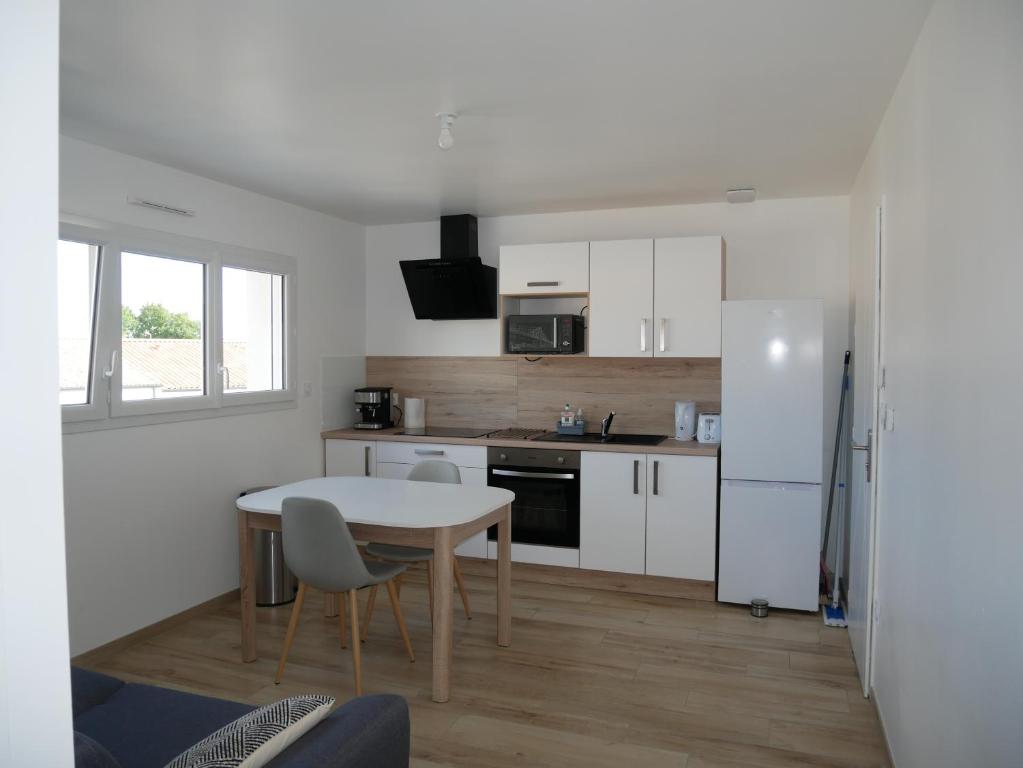 uma cozinha com armários brancos e uma mesa e cadeiras em Appartement lumineux au calme em La Roche-sur-Yon