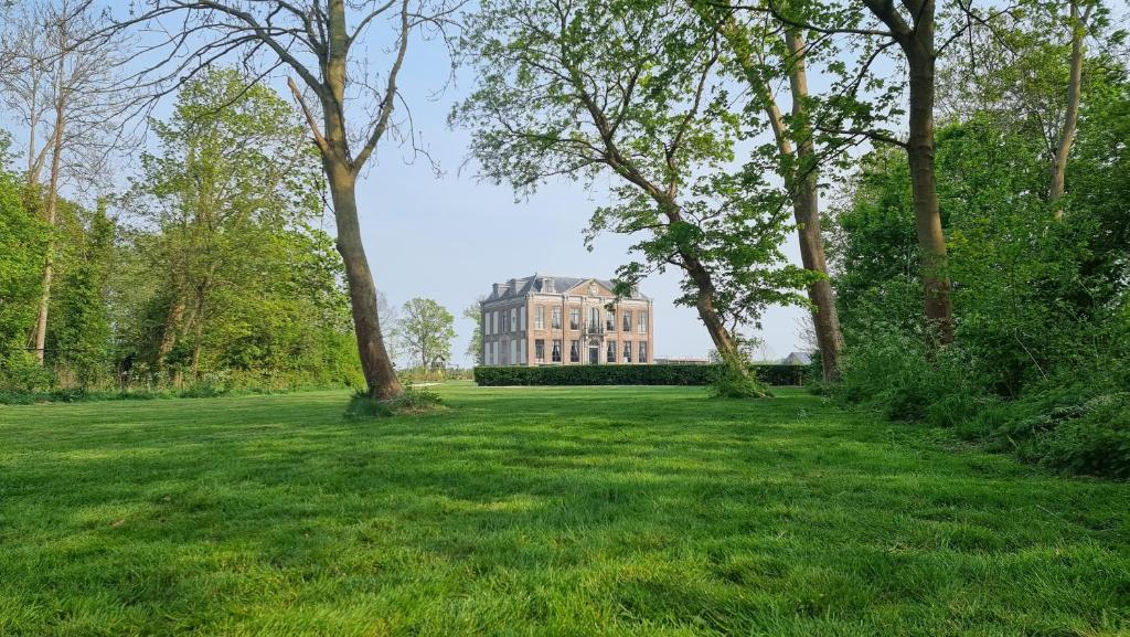 ein großes Haus inmitten eines Feldes mit Bäumen in der Unterkunft B&B Huis der Boede in Koudekerke