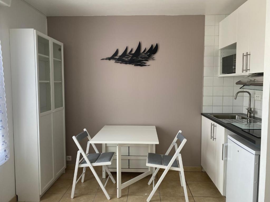 une cuisine avec une table blanche et quatre chaises dans l'établissement Résidence Fort de l'Eve - Studio à 380m plage M Hulot, commerces - St Marc sur Mer proche La Baule Pornichet avec Terrasse, à Saint-Nazaire