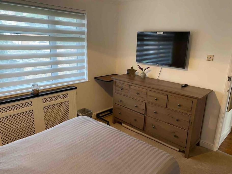 a bedroom with a dresser and a flat screen tv at One bed cozy flat in Dartford