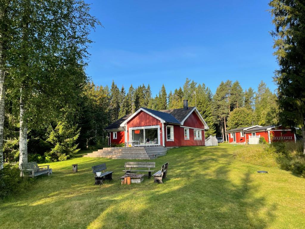 una casa roja con bancos delante en Beautiful house in the nature with private river access, en Luleå