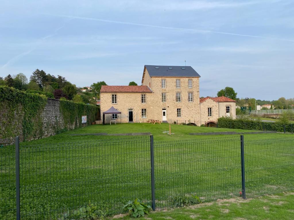 einen Zaun vor einem großen Haus in der Unterkunft Gîte moulin de Chaussac proche du Puy duFou in Saint-Laurent-sur-Sèvre