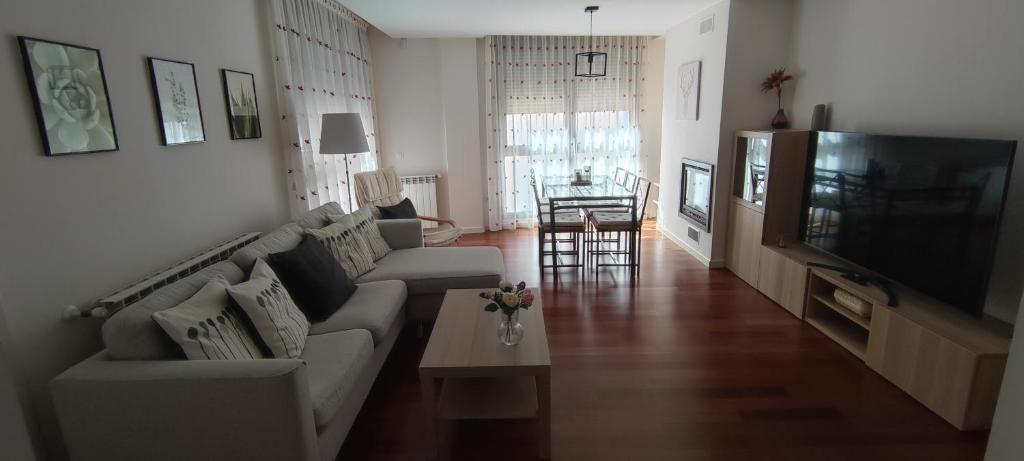 a living room with a couch and a tv at Apartamento Sabiñanigo Las Margas Pirineos, golf y piscina in Sabiñánigo