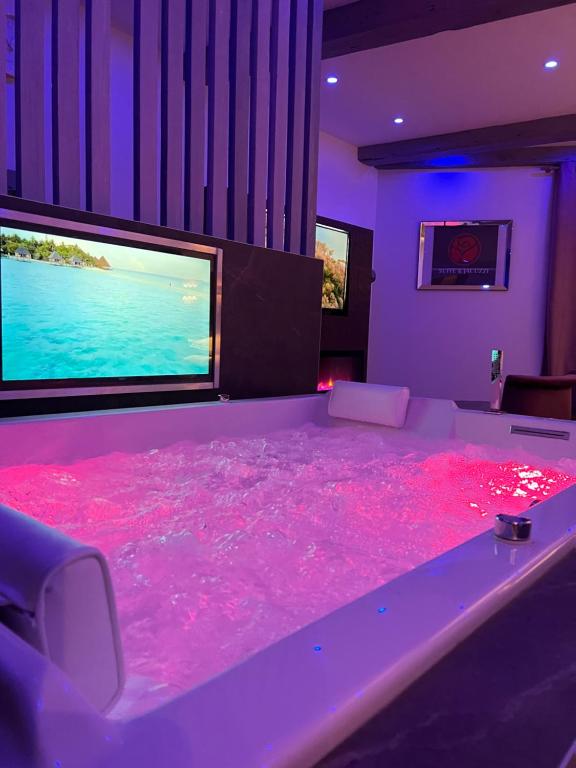 een kamer met een roze vloer en een grote tv bij Suite & Jacuzzi in Givors