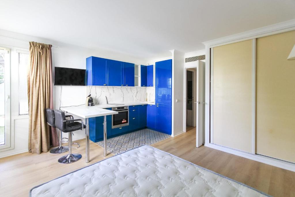 eine Küche mit blauen Schränken und einem weißen Bett in einem Zimmer in der Unterkunft Bright Studio Of 29m With Wifi Near Paris in Issy-les-Moulineaux