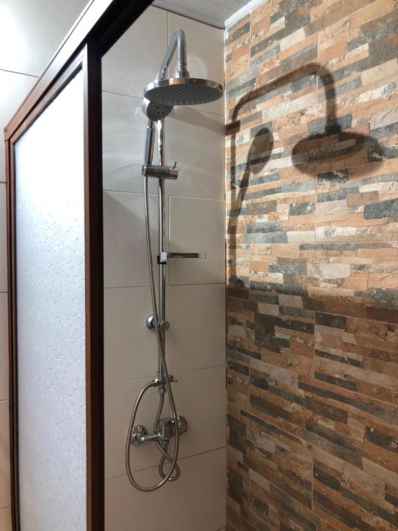 a shower in a bathroom with a brick wall at Cabañas Kalinaw in Las Trancas