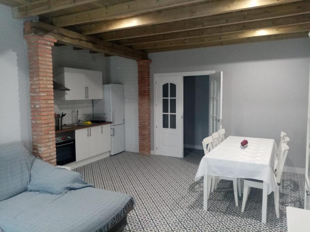 ein Wohnzimmer mit einem weißen Tisch und eine Küche in der Unterkunft Casa Rural La Plata in Aljucén