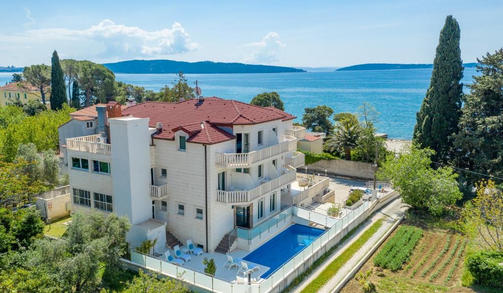  Elle offre une vue aérienne sur une grande maison blanche dotée d'une piscine. dans l'établissement Hotel Riva Kaštela with swimming pool, à Kaštela