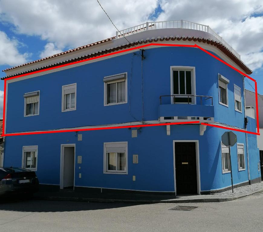 un edificio blu con una striscia rossa sopra di Alojamento Justo - vila de Montargil a Montargil