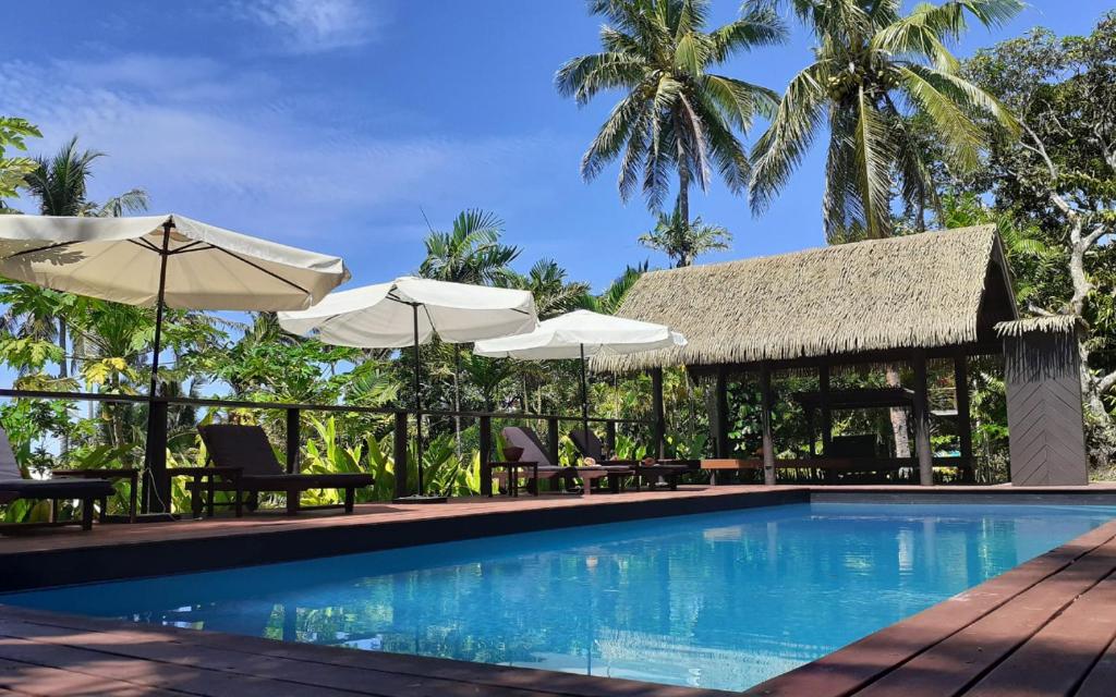 - une piscine dans un complexe avec des parasols et des chaises dans l'établissement Kaila Na Ua Resort, à Korotogo