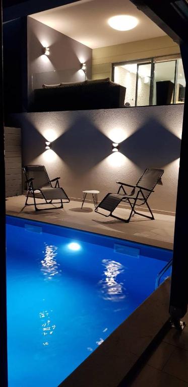 einen Pool mit Stühlen, einem Tisch und Lampen in der Unterkunft Apartman Mateo in Njivice